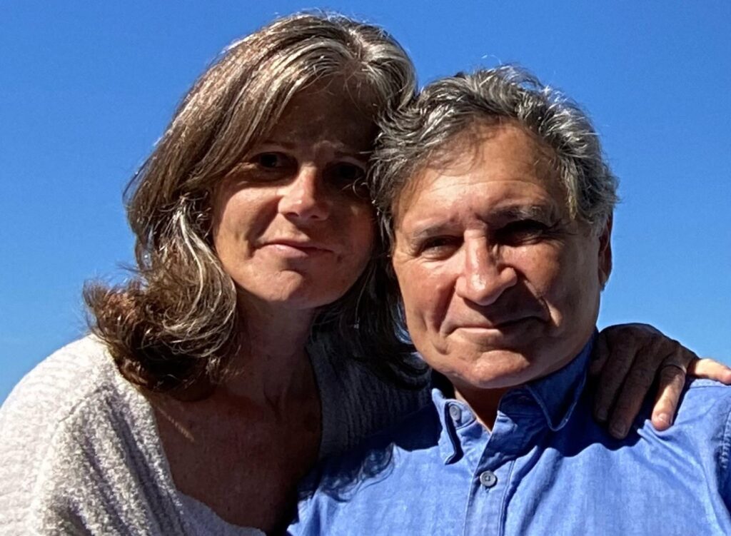 Smiling couple posing together outdoors against a clear blue sky.