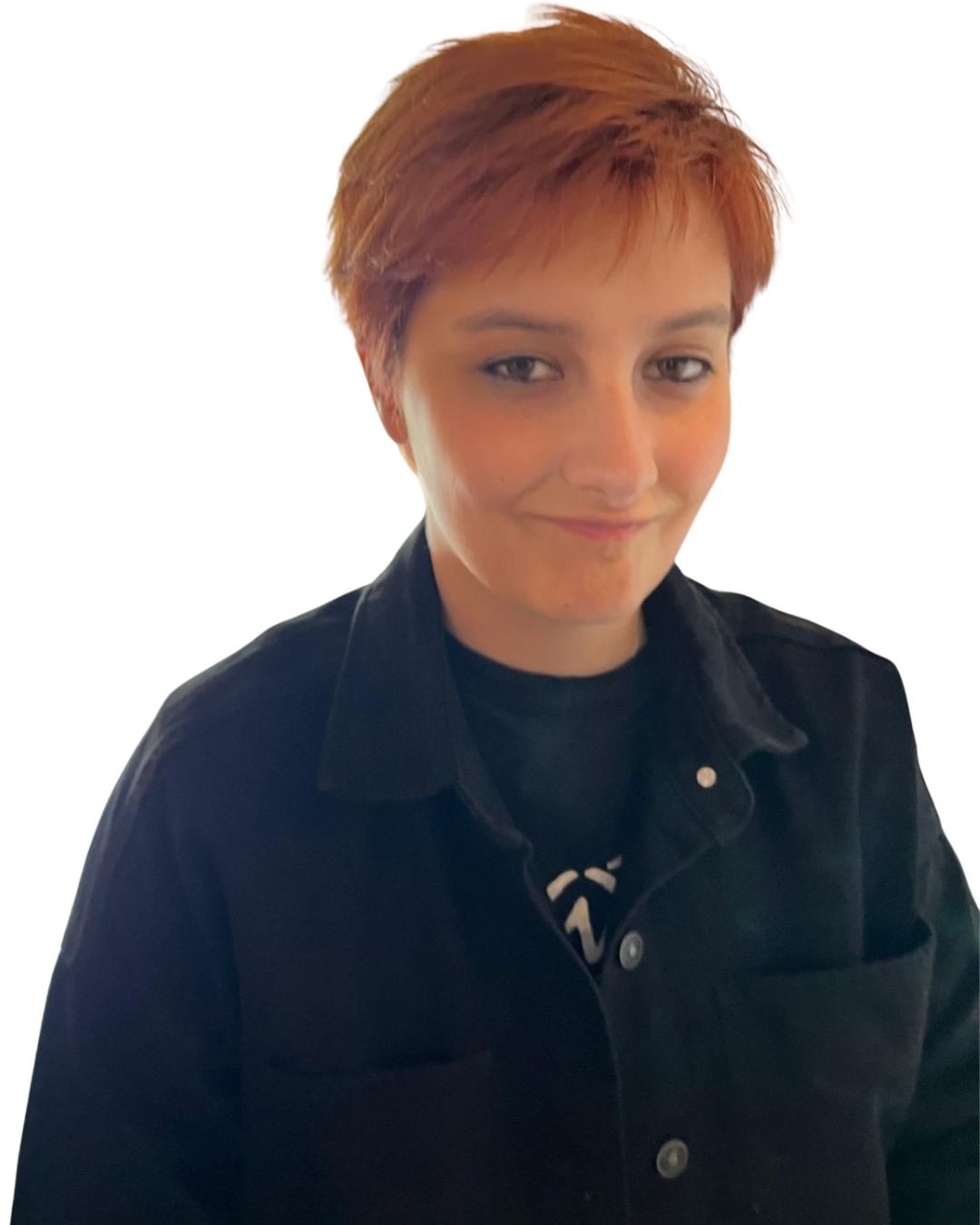 Person with short copper-red hair wearing a black jacket, looking at the camera with a subtle smile.