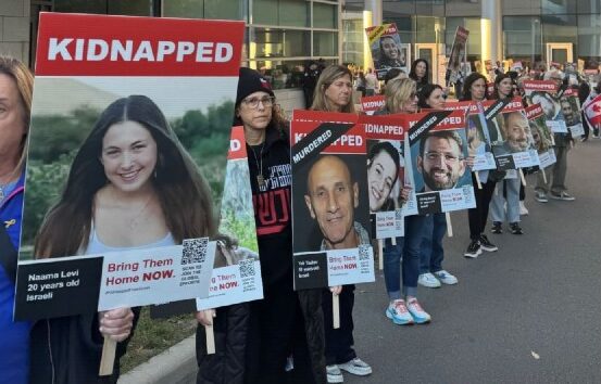 Protesters line up outdoors, each holding large missing-person signs with the word 'KIDNAPPED' and photos/names of missing people.