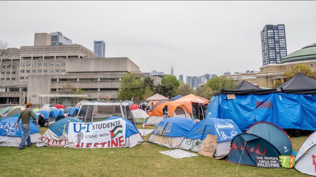 Tents set up in a campus park for a student protest, with banners showing Palestine solidarity.