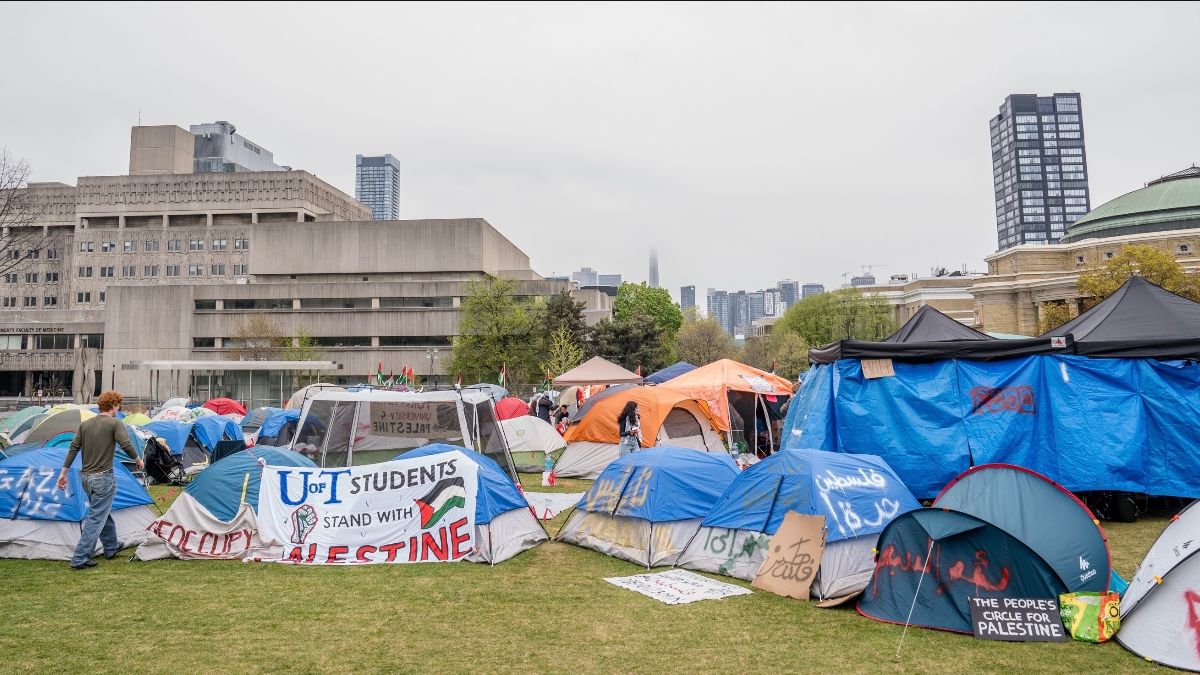 Tents set up in a campus park for a student protest, with banners showing Palestine solidarity.