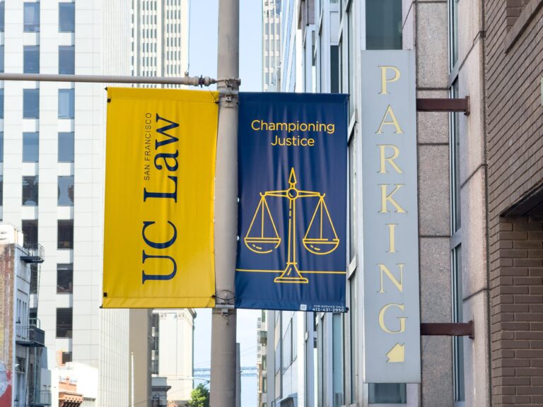 Blue banner reads 'Championing Justice' with a scales-of-justice icon; yellow banner for a law firm beside it; vertical 'PARKING' sign on the building.
