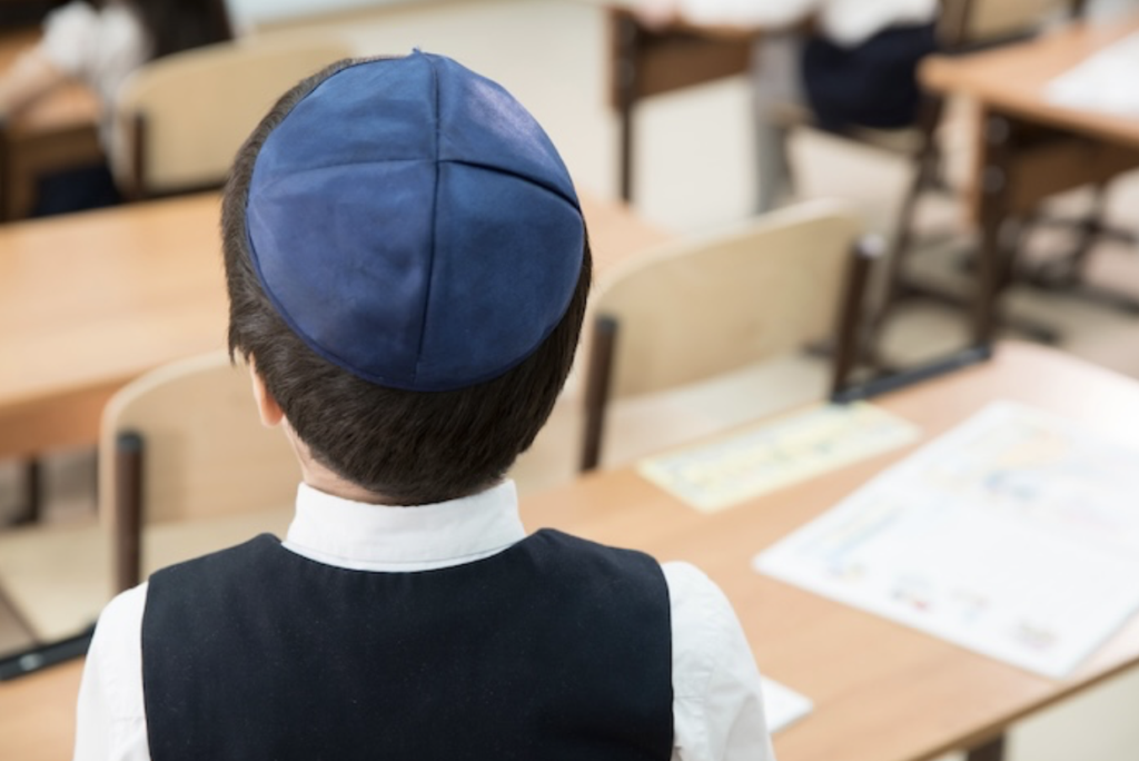 Jewish child wearing a kippah in a classroom.
