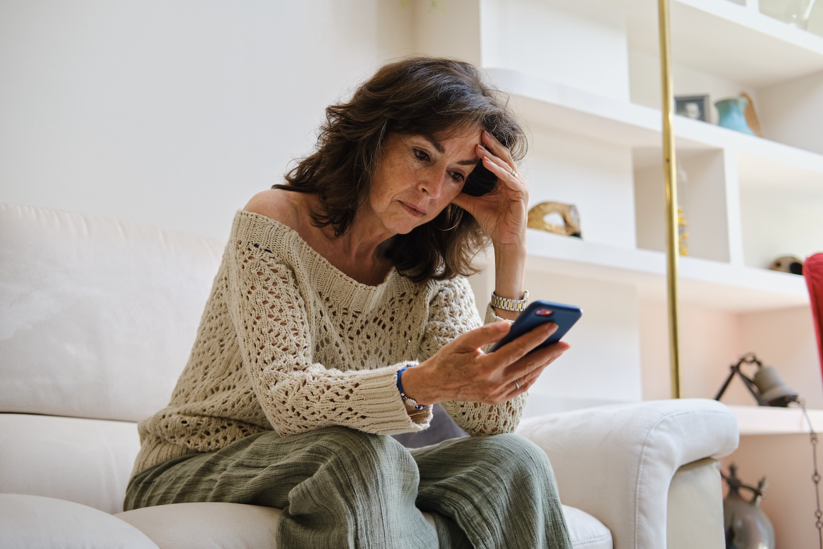 Concerned older woman looking at her phone at home.